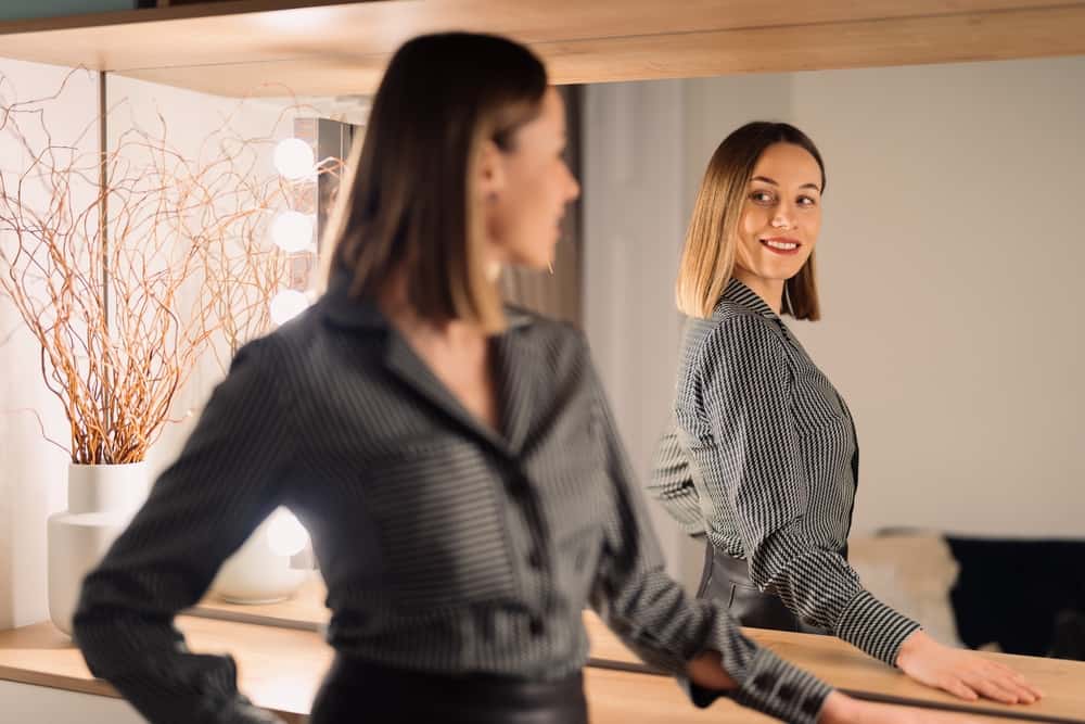 attractive-Woman-looking-at-her-reflection-into-the-mirror-indoors