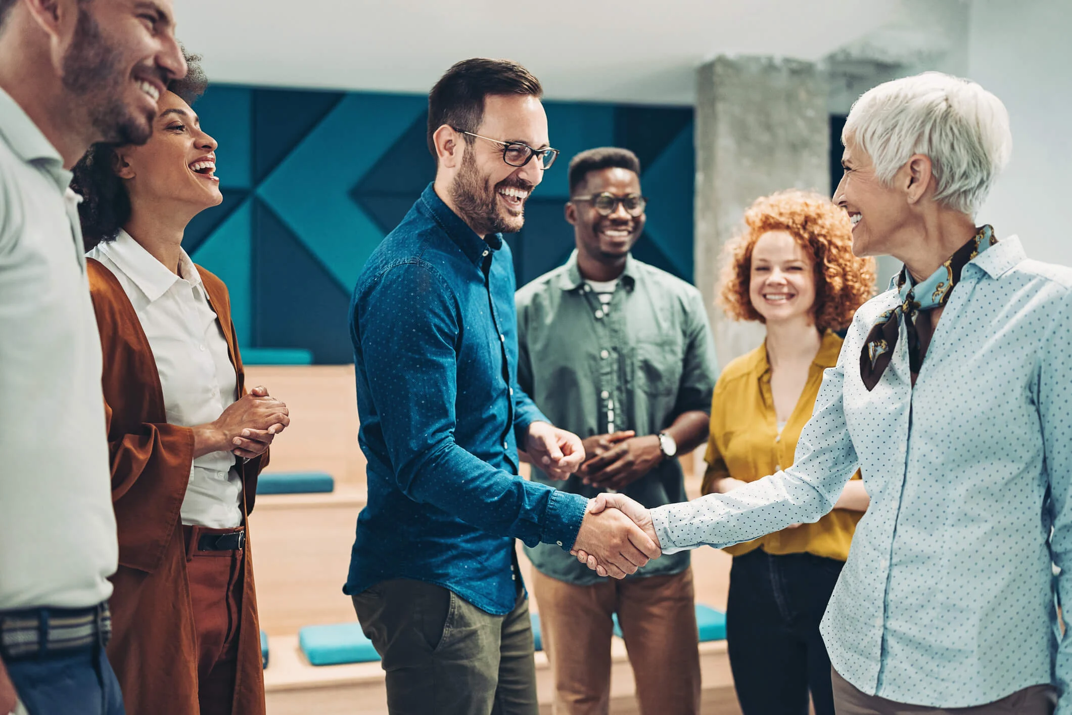gender diverse group of coworkers in a circle shaking hands and smiling