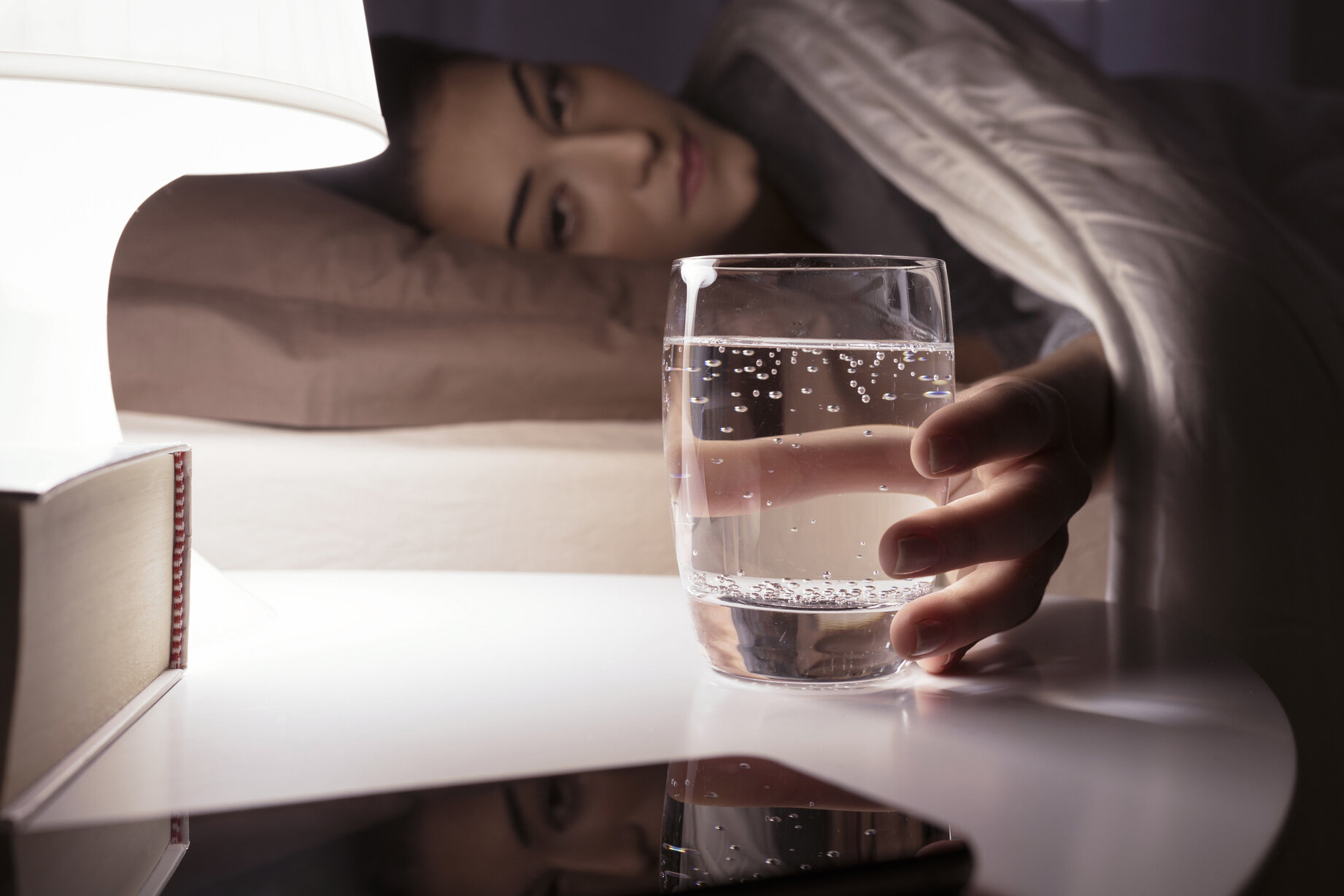 Woman drinking a glass of water at night before she sleep